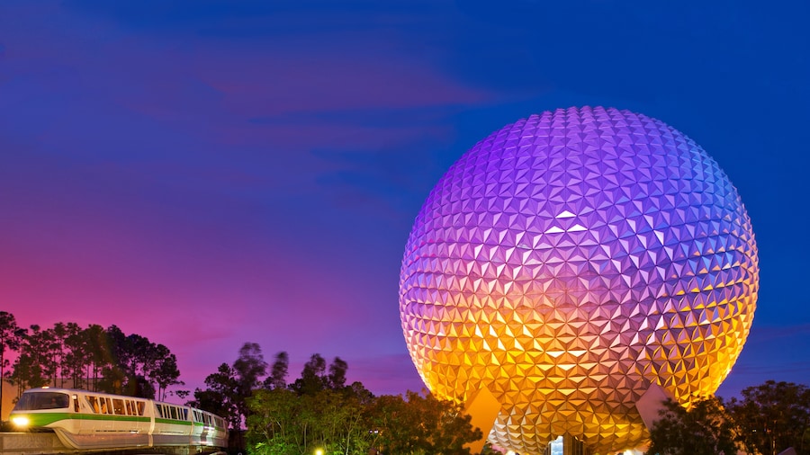 A monorail glides by Spaceship Earth at sunset