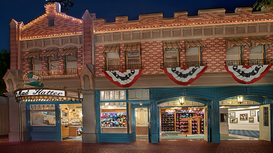 Patriotic flags cascading from the storefront as lights outside The Mad Hatter illuminate the night