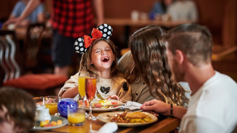 A young girl and her parents enjoying breakfast together at a Disney restaurant