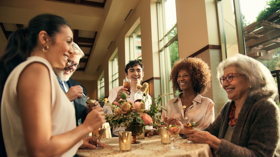 Visitantes en una mesa de coctel disfrutando de bocadillos y bebidas