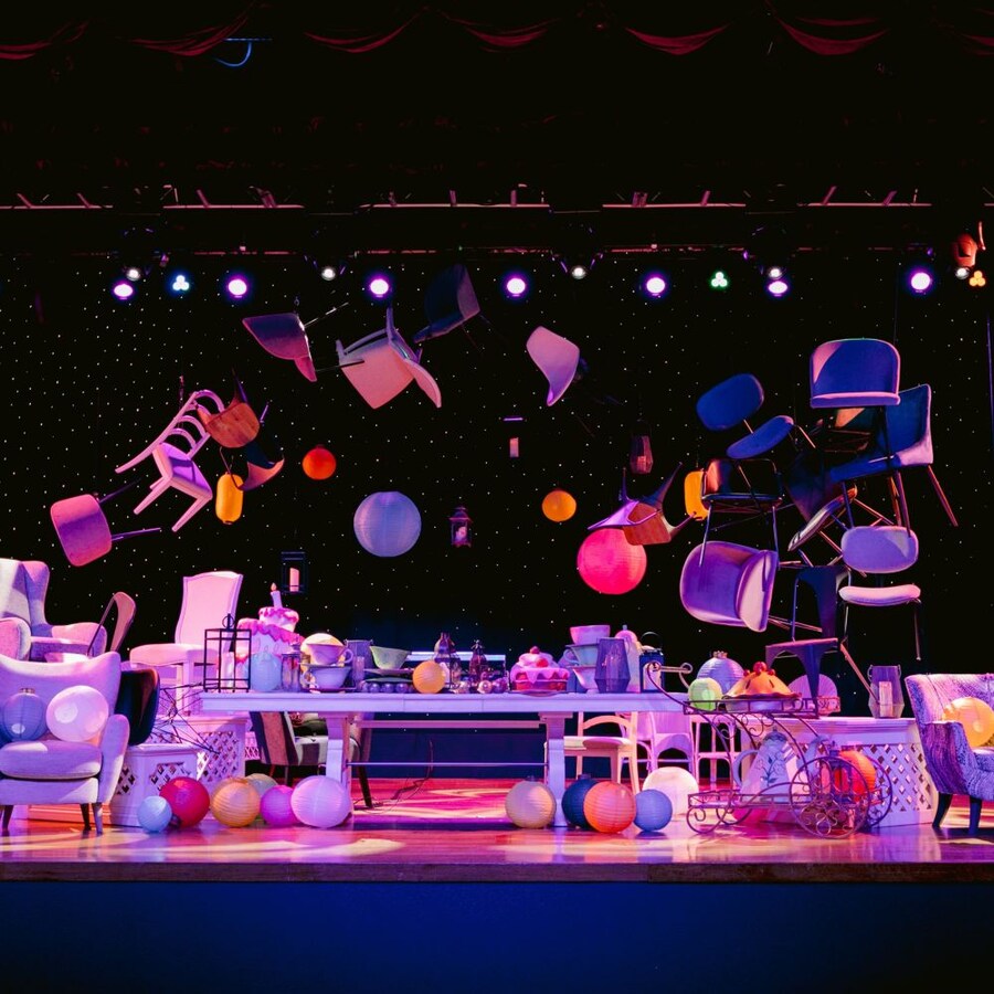 Un escenario en un espacio para eventos con muebles y faroles sobre el escenario y suspendidos en el aire