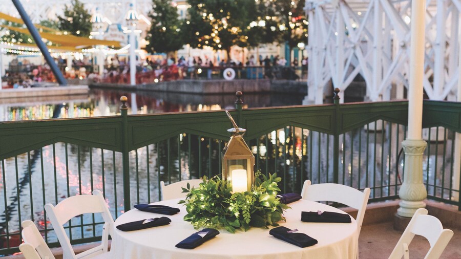 Un espacio de recepción al aire libre con mesas, sillas y arreglos florales junto a Paradise Bay en Disney’s California Adventure Park