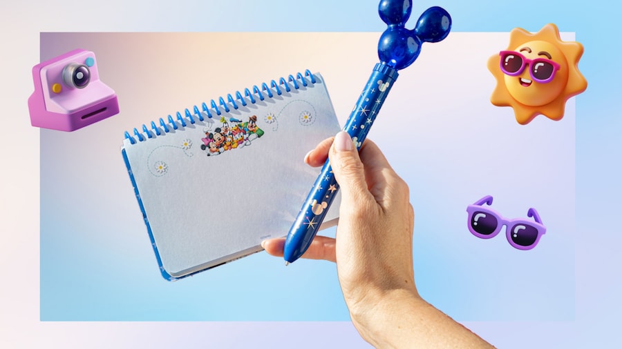 A hand holding a pen and a Disney autograph book