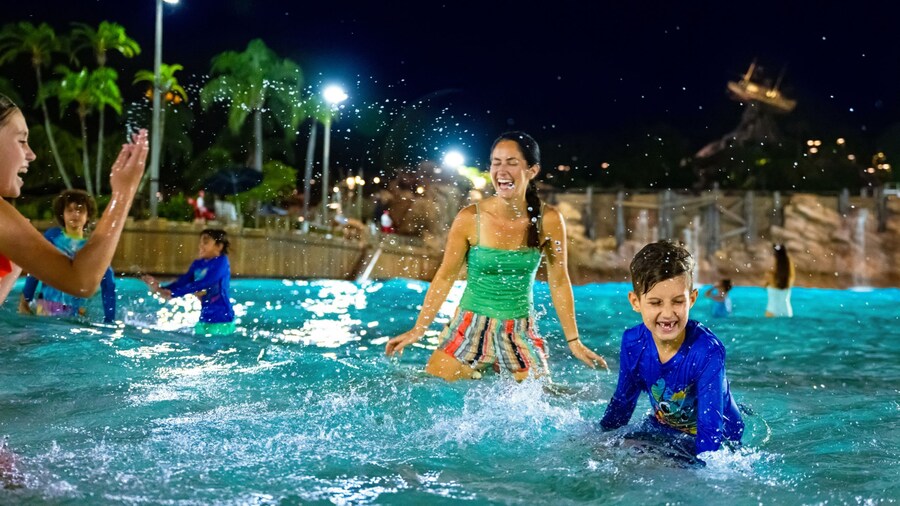 Two young Guests with their mother playing in the waters of Typhoon Lagoon Surf Pool during Disney H2O Glow After Hours