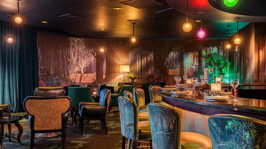 The bar area at the Broken Spell Lounge featuring a haunted forest theme, stools, lamps and place settings