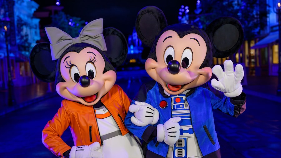Minnie Mouse wearing a Rebel pilot inspired outfit and Mickey Mouse dressed in an R2 D2 themed jacket at night