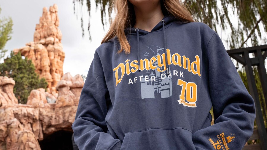 A Guest posing in front of Big Thunder Mountain Railroad with a Disneyland After Dark 70 Years of Favorites hoodie