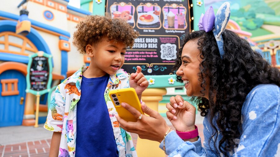 A boy and a woman placing a mobile order on her phone in front of Café Daisy