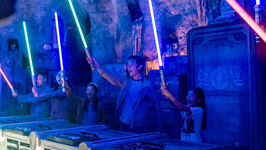 Guests holding up the glowing lightsabers that they built at Savi’s Workshop