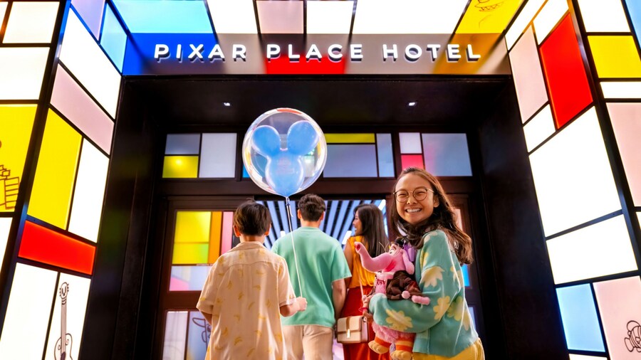 A family of 4 going into the entrance of Pixar Place Hotel