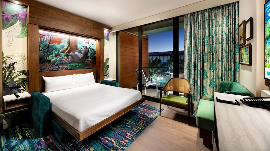 A hotel villa studio with 2 chairs, a wall bed, deck, deck furniture and 'The Jungle Book' themed artwork