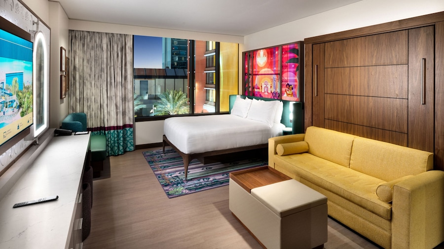 A hotel villa studio with a bed, TV, couch and 'The Princess and the Frog' themed artwork