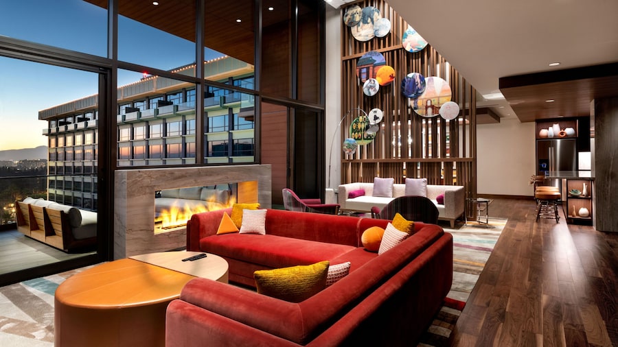 A hotel villa living area with 2 couches, 2 chairs, a fireplace and a deck with deck furniture