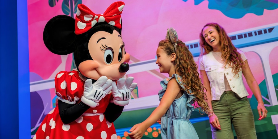 Una madre y su hija pequeña saludan a Minnie Mouse