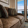 Sofa with textured luxury upholstery and throw pillows next to glass door that opens to veranda