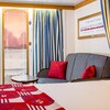 Stateroom with dividing curtain, dresser, TV, glass door, sofa with coffee table and bed