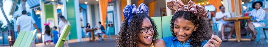 2 niñas sonrientes con diademas de diseñador de Minnie Mouse están sentadas juntas