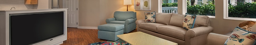 Deux canapés et un fauteuil avec un pouf placés devant un grand téléviseur à écran plat dans un salon