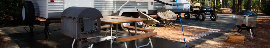 Table de pique-nique à côté d’un barbecue et d’un véhicule récréatif
