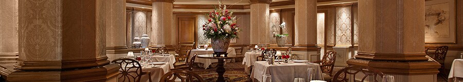 Salle à manger officielle au Victoria & Albert’s, avec un bouquet de fleurs et des tables dressées avec des services en porcelaine raffinés