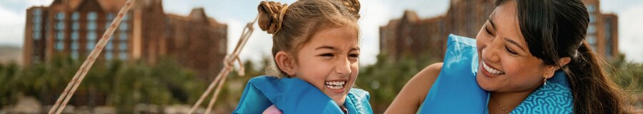 A mother and her young daughter, smiling and relaxing on the deck of a small boat