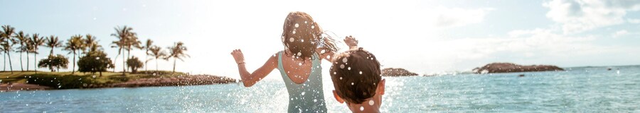 A girl and a boy splashing in the shallow ocean