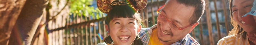 Una niña con orejas de Mickey Mouse ríe con su familia