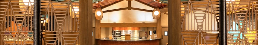 Salão de jantar com arquitetura com inspiração polinésia, incluindo um mural no teto e detalhes em madeira natural