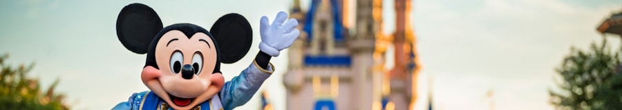 Mickey Mouse waving to the camera while standing near Cinderella Castle in Magic Kingdom park