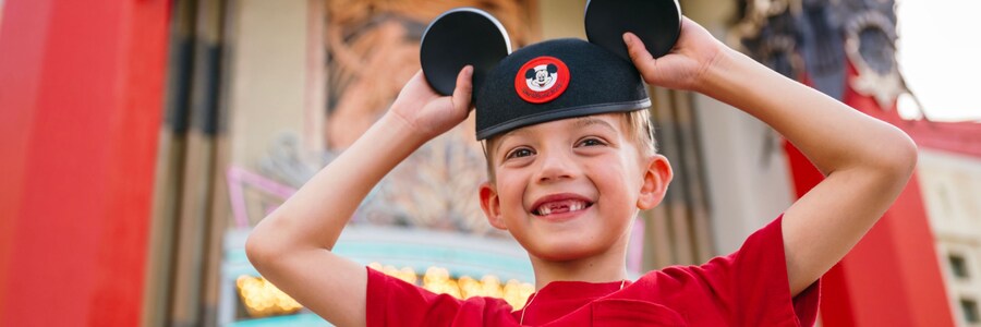 A smiling boy wearing a Mickey Mouse ear hat while standing in front of Grauman's Chinese Theatre.