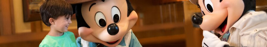 Un niño sonríe mientras Mickey Mouse y Minnie Mouse lo saludan en Disney’s Grand Californian Hotel and Spa.