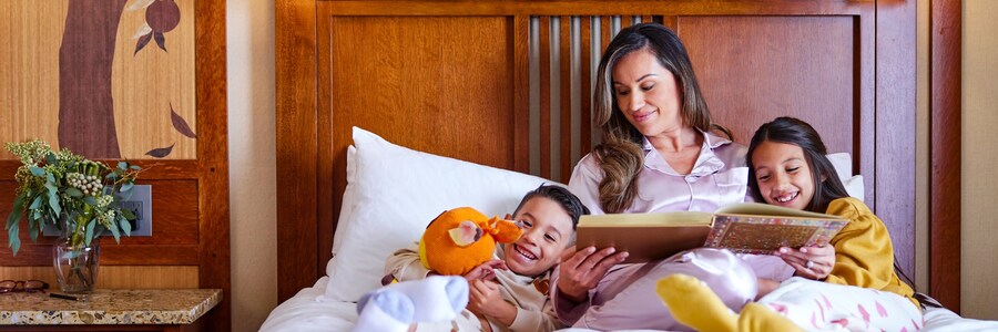 A mother reads a bedtime story to her kids in a Disneyland Resort hotel room