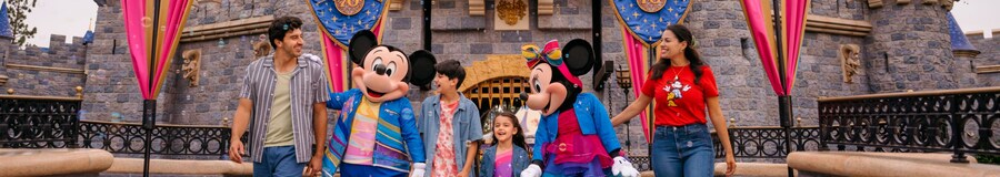 Family walking with Mickey and Minnie Mouse in front of the Disneyland castle during the 70th anniversary celebration