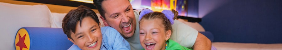 A father and his 2 kids play around in a Disneyland Resort hotel room