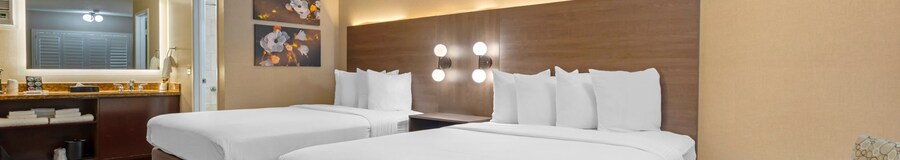 A Best Western Plus Stovall's Inn Standard Room with 2 beds, a nightstand, a sink, a mirror, a bathroom and 2 armchairs