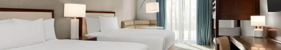 A hotel room with a desk, TV, balcony, nightstand, 2 queen beds and 2 bunk beds