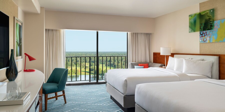 A hotel room with 2 queen beds, a chair and balcony at the Hyatt Regency Grand Cypress Resort