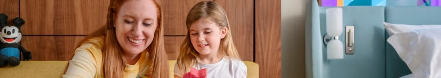 Mother and daughter enjoying a fruit snack together, sitting on a sofa at a Disneyland Resort hotel. 