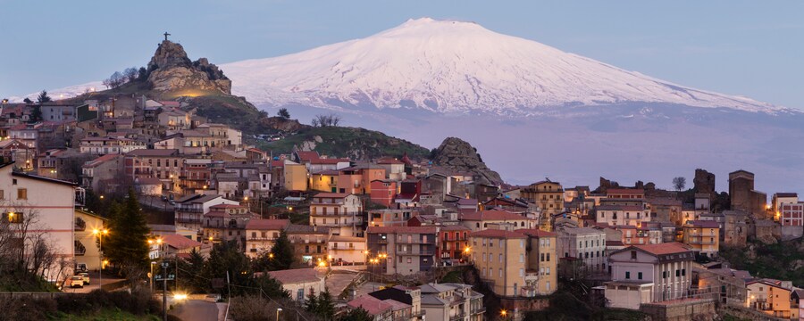 Una aldea construida sobre una ladera, junto a un volcán cubierto de nieve
