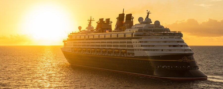 Un crucero de Disney navega por el océano, hacia el sol que se pone en el horizonte
