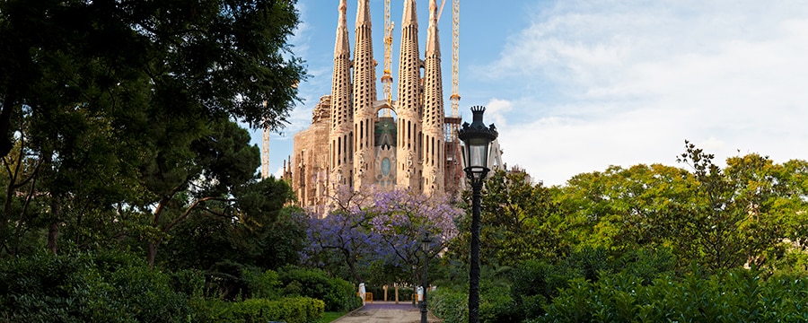 Sagrada Familia church in Barcelona, surrounded by trees and lush foliage Sagrada Familia church in Barcelona, surrounded by trees and lush foliage