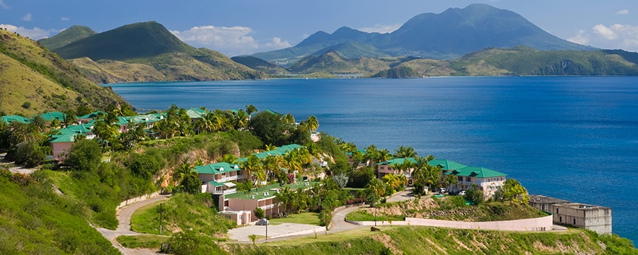 Buildings on a grassy hillside overlooking a beach in St. Kitts Buildings on a grassy hillside overlooking a beach in St. Kitts