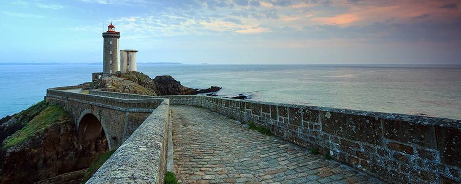 Un sendero de piedra y un puente cerca de un faro y del océano