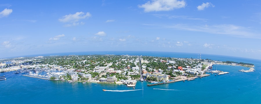 Two boats speed in the waters around an island crowded with buildings Two boats speed in the waters around an island crowded with buildings