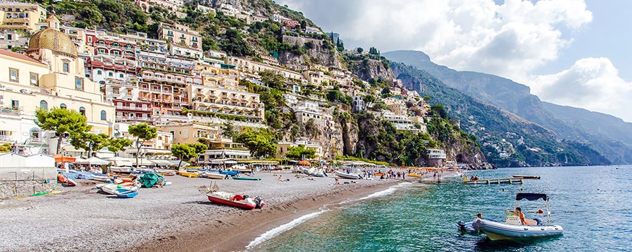 Una playa con botes, y edificios y colinas en la costa Una playa con botes, y edificios y colinas en la costa