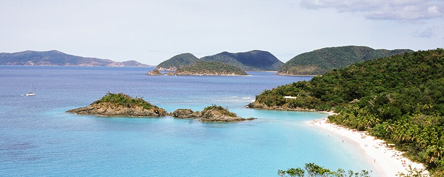 Aerial shot of a bay with several islands covered in plants and a beach in the foreground
