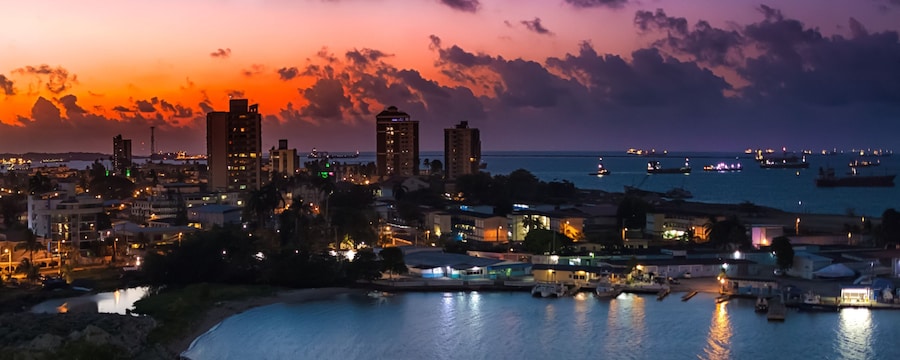 Skyline of Colón, Panama at sunset with illuminated buildings and ships anchored offshore Skyline of Colón, Panama at sunset with illuminated buildings and ships anchored offshore