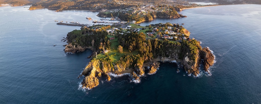 A craggy islet next to a mainland with rolling hills and mountains A craggy islet next to a mainland with rolling hills and mountains
