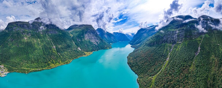 A fjord surrounded by towering mountains with a scattering of houses along the shoreline