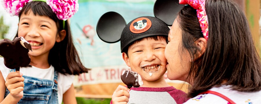 A mom and her two children enjoy Mickey ice cream bars